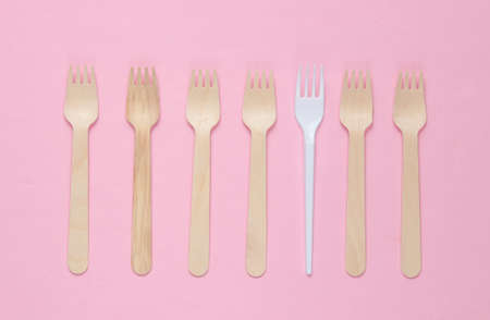 Minimalistic environmental concept. Wooden and plastic forks on a pink pastel background. Creative eco backgroundの写真素材