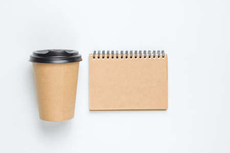 Disposable empty coffee cup with natural materials  and craft notebook on a white background. Eco...