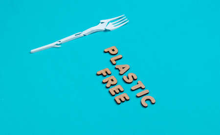 Environmentally friendly still life. Broken plastic fork on blue background with the word eco.の写真素材
