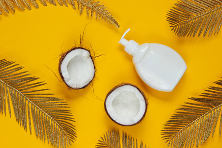 Minimalistic beauty still life. Two halves of chopped coconut and white bottle of cream with golden...