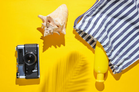 Creative vacation on sea background. Beach accessories on yellow background with a shadow from tropical palm leaf. Top viewの写真素材