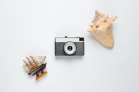 Minimalistic travel still life. Seashells, retro camera, decorative ship on white background. Top viewの写真素材