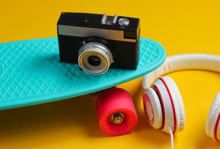 Hipster outfit. Skateboard with headphones on yellow background. Creative fashion minimalism. Trendy retro 80s style. Minimal summer funの写真素材
