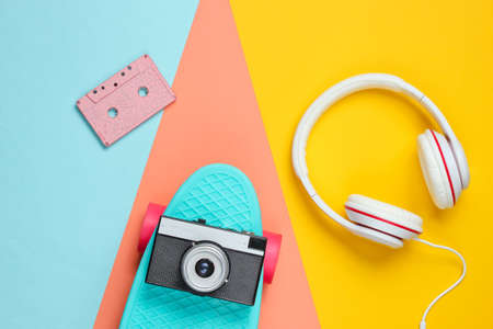Hipster outfit. Skateboard with headphones, audio cassette on colored background. Creative fashion minimalism. Trendy retro 80s style. Minimal summer fun. Music concept. Top viewの写真素材