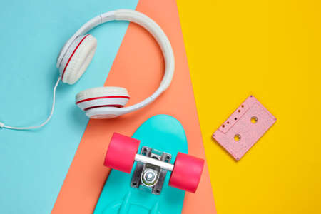 Hipster outfit. Skateboard with headphones, audio cassette on purple background. Creative fashion minimalism. Trendy retro 80s style. Minimal summer fun. Music concept. Top viewの写真素材