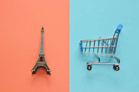 Shopping in Paris minimalistic concept. Shopping trolley, eiffel tower figurine on pastel colored background. Top viewの写真素材
