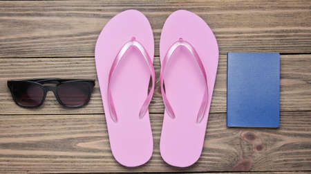 The concept of vacation on the beach, tourism. Summer traveler background. Flip flops, passport, sunglasses on wooden background. Top view. Flat layの写真素材