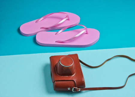 Flip flops and retro camera on blue paper background. Trip, vacation concept. Summer fashion, holiday. Beach accessories.の写真素材