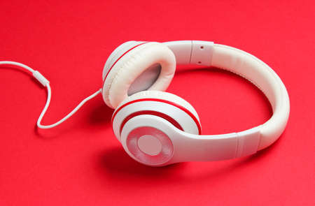 Classic white wired headphones on red paper background. Retro style. 80s. Pop culture. Music loverの写真素材