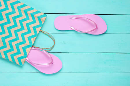 New pink flip flops in a paper bag on blue wooden background. Shopping concept. Top viewの写真素材
