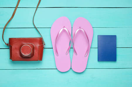 The concept of vacation on the beach, tourism. Summer traveler background. Flip flops, retro camera, passport on blue wooden background. Top view. Flat layの写真素材