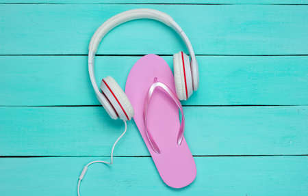 Flip flop and headphones on blue wooden background. Summertime relax. Summer vacation. Beauty and fashion. Top view. Flat layの写真素材