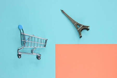 Shopping in Paris minimalistic concept. Shopping trolley, eiffel tower figurine on pastel colored...