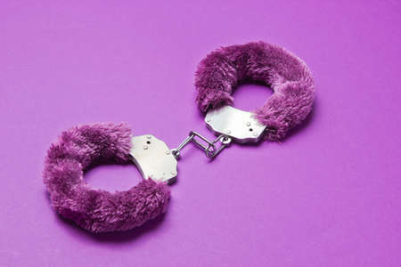 Handcuffs for sex games on purple background. Sexual bdsm toy. Fetish, erotic concept.の写真素材