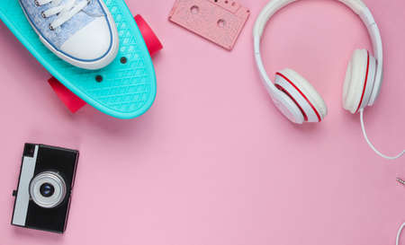 Hipster outfit. Skateboard, headphones, audio cassette, sneakers, retro camera on pink background. Creative fashion minimalism. Minimal summer fun. Pop art. 80s. Copy space. Top viewの写真素材