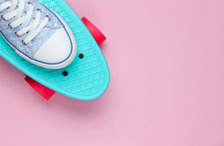 Hipster sneakers on skateboard top view on pink background. Minimalism fashion conceptの写真素材