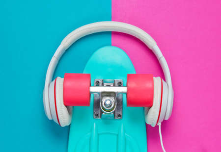 Hipster outfit. Skateboard with headphones on colored background. Creative fashion minimalism. Trendy old fashionable style. Minimal summer fun. Music concept. Top viewの写真素材