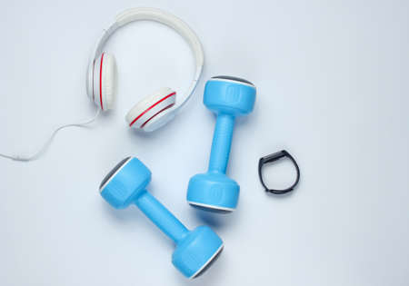 Dumbbells, smart bracelet, headphones on a white background. Minimalistic sport concept. Top view.の写真素材