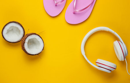 Flip flop with headphones, coconut on yellow background. Summertime relax. Summer vacation. Beauty and fashion. Top view. Flat layの写真素材
