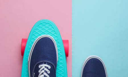 Hipster sneakers on skateboard top view on pink blue pastel background. Minimalism fashion conceptの写真素材