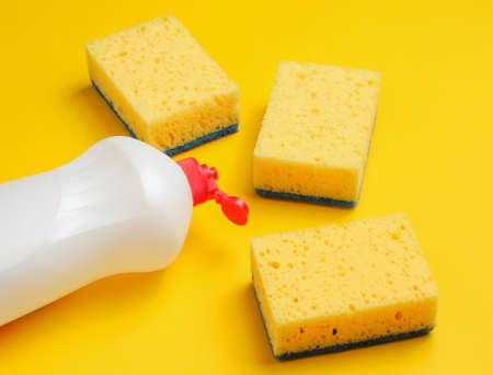 Set of housewives for washing dishes. Dishwasher. Bottle of washing utensils, sponges on yellow...