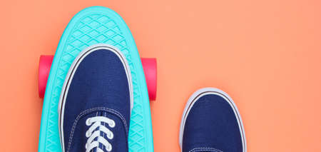 Hipster sneakers on skateboard top view on coral background. Minimalism fashion conceptの写真素材