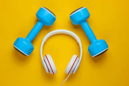 Sports equipment on yellow background. Sport lifestyle. Dumbbells, headphones. Fitness concept. Top view, minimalism, flat layの写真素材
