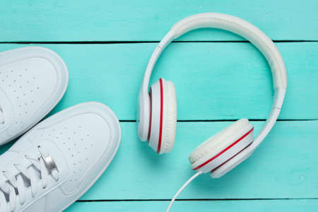 White Sneakers with headphones on blue wooden background. Music concept. Flat lay, minimal.の写真素材