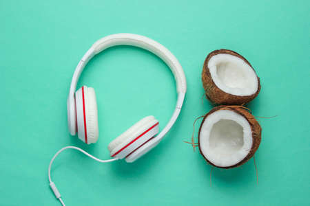 Music lover creative concept. Summer background. white classic headphones, coconut halves on a blue background. Top viewの写真素材
