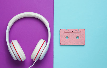 Audio cassette and headphones on purple blue background. Retro music concept. Vintage background....