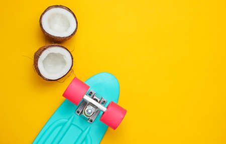 Creative summer concept. Skateboard, coconut halves on a yellow background. Copy space, top viewの写真素材