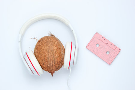 Audio cassette and headphones with coconut on white background. Retro music concept. Vintage background. Disco party. Top viewの写真素材