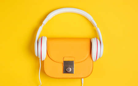 Minimalistic fashion concept. Fashionable yellow leather bag with headphones on a yellow background. Top viewの写真素材