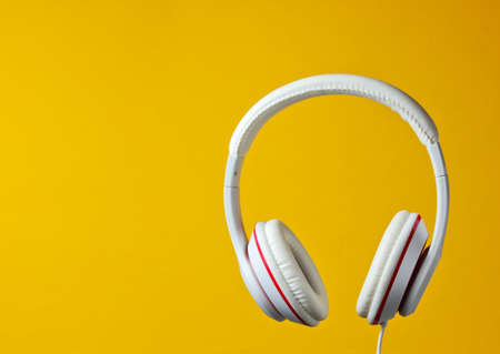 White classic wired headphones isolated on yellow background. Retro style. Minimalistic music concept.の写真素材