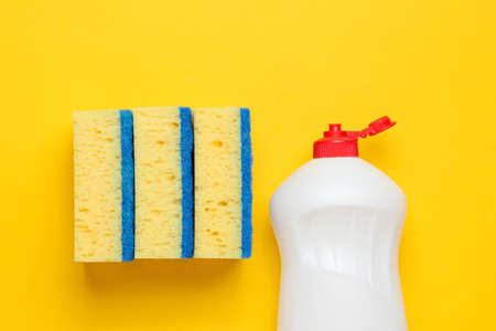 Set of housewives for washing dishes. Dishwasher. Bottle of washing utensils, sponges on yellow background. Top view.の写真素材