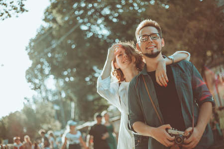 Young hipster couple in love tourist walking along a city street with retro cameraの写真素材