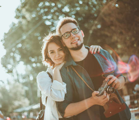 Young hipster couple in love tourist walking along a city street with retro camera