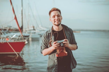 Portrait of a young cheerful hipster on the background of the seaの写真素材