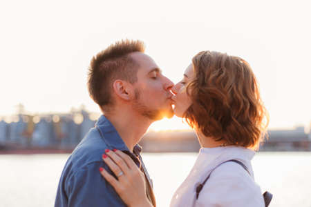 Portrait of a young kissing couple of lovers at sunset on the sea