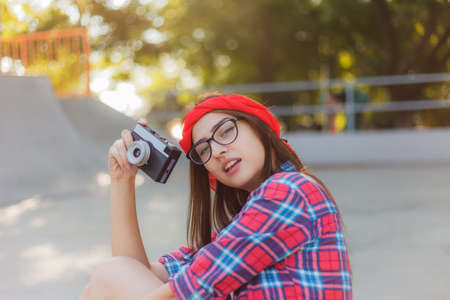 Stylish hipster girl holding retro camera in hands on a bright sunny day. Youth conceptの写真素材