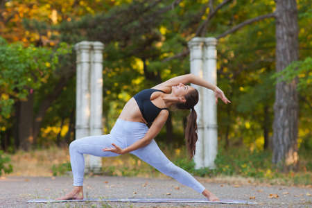 Yoga and fitness. Young woman practicing balancing yoga pose outdoor. Gymnastic exercise in park.