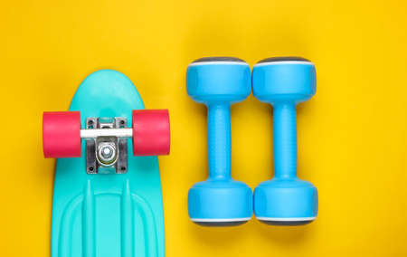 Cruiser board and dumbbell on a yellow background. Top viewの写真素材