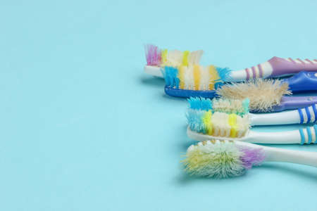 Old used toothbrushes on blue background. Dental care concept. Top view. Copy space