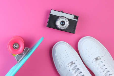 Hipster outfit. Cruiser board, sneakers, retro film camera on pink background. Top viewの写真素材