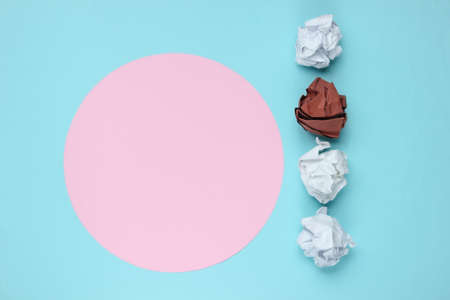 Crumpled Paper Balls on blue background with pink pastel circle for copy space. The concept of uniqueness. Minimalistic business still life. Top view.の写真素材