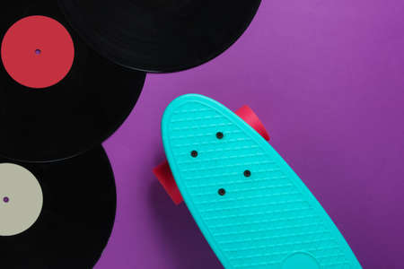 Cruiser board and vinyl records on a purple background. Youth retro style concept. 80s. Top viewの写真素材