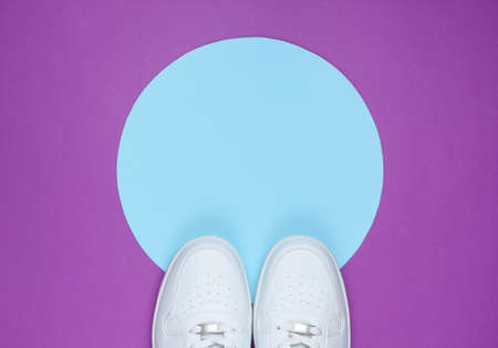 White sneakers on purple background with blue pastel circle for copy space. Youth hipster concept. Top viewの写真素材