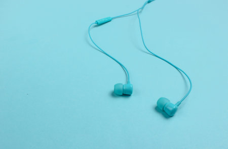 Wired earphones on blue background close-up. Music lover
