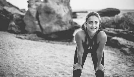 Tired attractive fitness woman in sportswear on a wild beach.の写真素材
