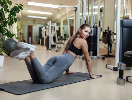 Slim fit woman in sportswear getting ready doing push-ups from the floor in the gym. Healthy...